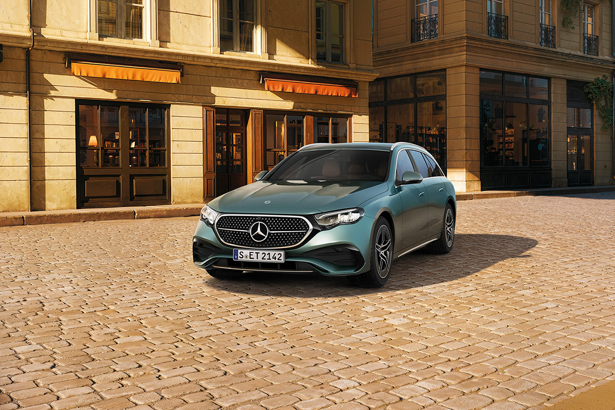 Auf dem Bild steht ein grünes Kombi‑Fahrzeug der Marke Mercedes‑Benz auf einer gepflasterten Fläche. Das Auto ist schräg von vorne dargestellt, sodass die Front und die linke Seite sichtbar sind. Es verfügt über schmale LED‑Scheinwerfer, einen geschlossenen Kühlergrill mit dem Mercedes‑Benz‑Logo in der Mitte sowie mehrspeichige Leichtmetallräder.