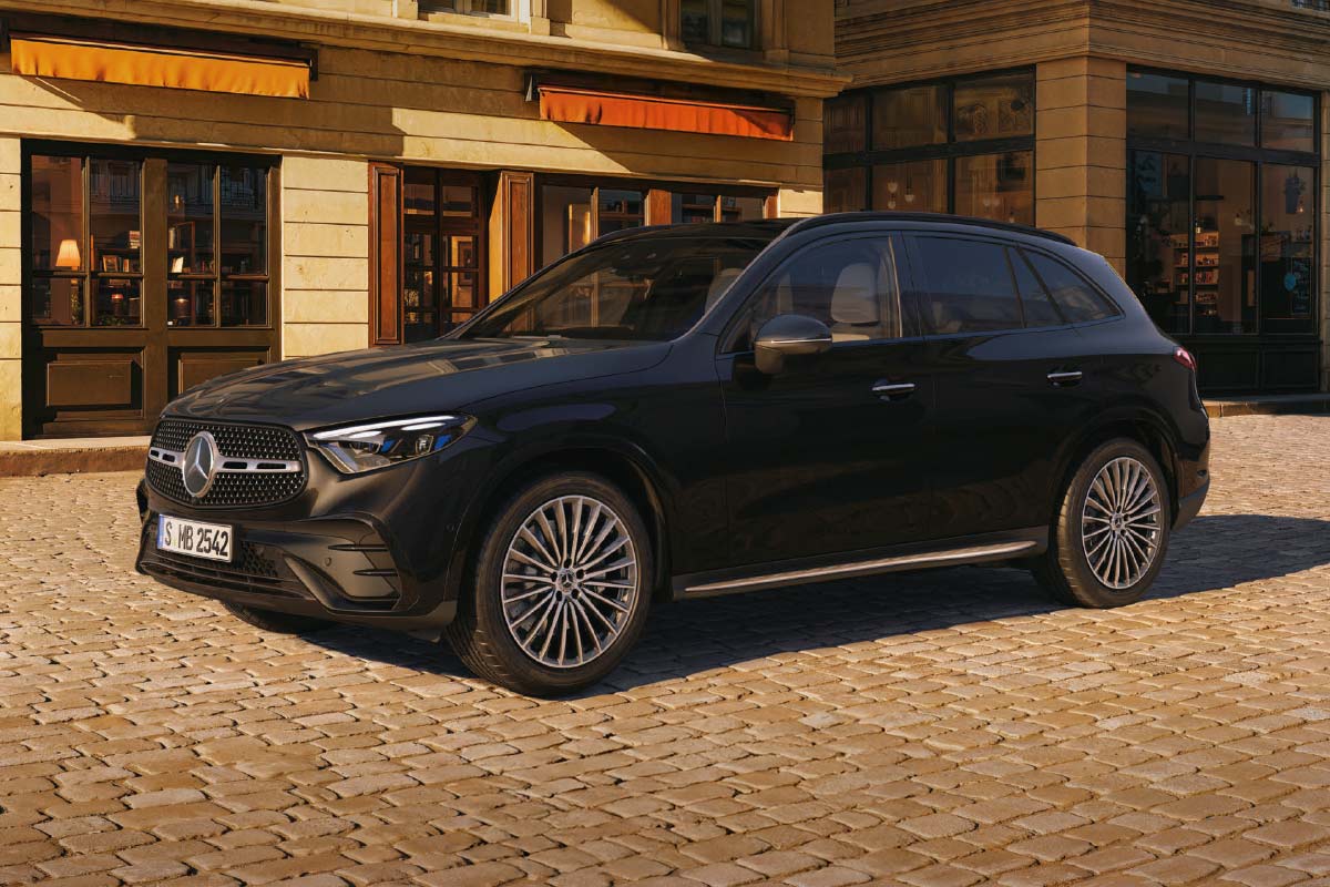 Auf dem Bild steht ein graues SUV‑Fahrzeug der Marke Mercedes‑Benz auf einer gepflasterten Straße. Das Auto ist schräg von vorne zu sehen, sodass die Fahrzeugfront und die linke Seite sichtbar sind. Das Fahrzeug besitzt große Leichtmetallräder, markante LED‑Scheinwerfer und einen Kühlergrill mit dem Mercedes‑Benz‑Logo in der Mitte. 