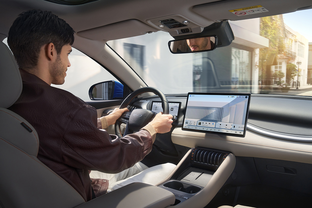 Innenansicht eines modernen Fahrzeugs mit Lenkrad grossem Touchscreen und Mittelkonsole Person sitzt am Steuer uebersichtliche Anzeige und Bedienelemente fuer Navigation und Fahrzeugfunktionen waehrend der Fahrt