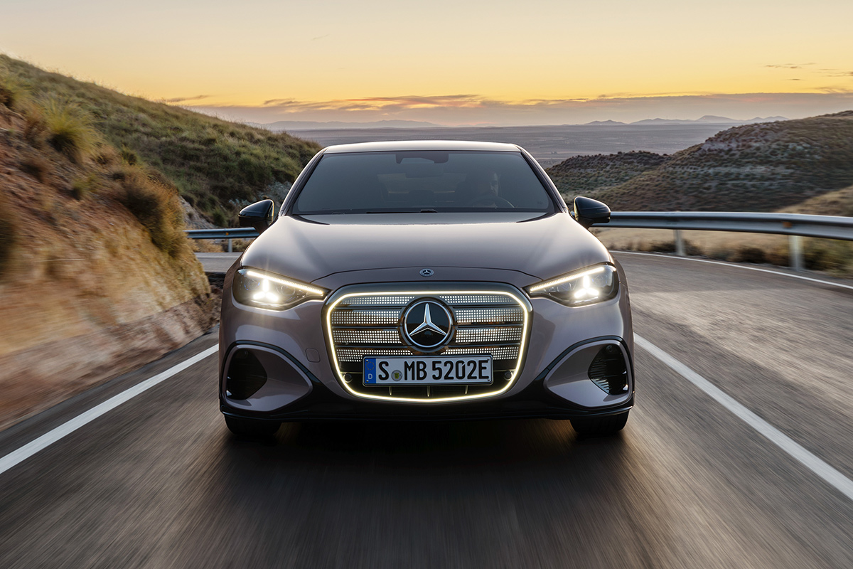 Nahaufnahme der Frontpartie einer silbergrauen Mercedes Benz C Klasse. Zu sehen sind der markante Frontgrill mit zentralem Stern und leuchtendem Wabenmuster sowie ein moderner LED Scheinwerfer.