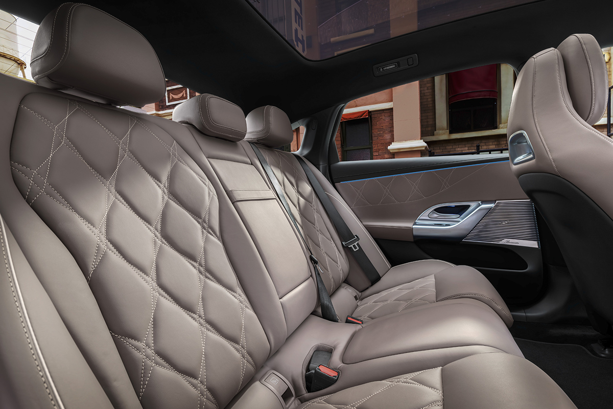 Rueckbank einer Mercedes Benz C Klasse mit hochwertigen beigen Ledersitzen und Rautensteppung. Sichtbar sind die Tuerverkleidung mit Ambientebeleuchtung und ein Teil des Panoramadachs.