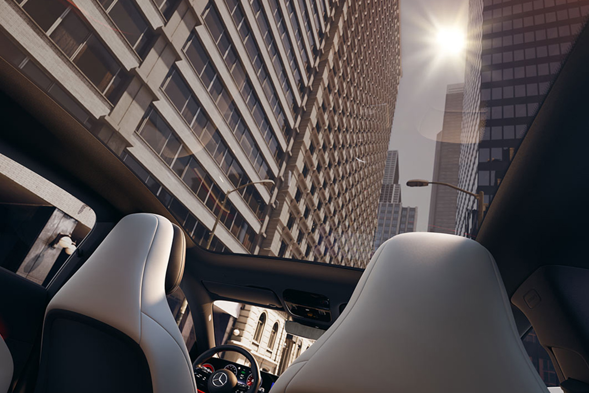 Blick aus dem Innenraum eines Mercedes durch das Panoramadach auf hohe Stadthauser, waehrend die Sonne zwischen den Gebaeuden scheint; Vordersitze in hellem Leder sichtbar.