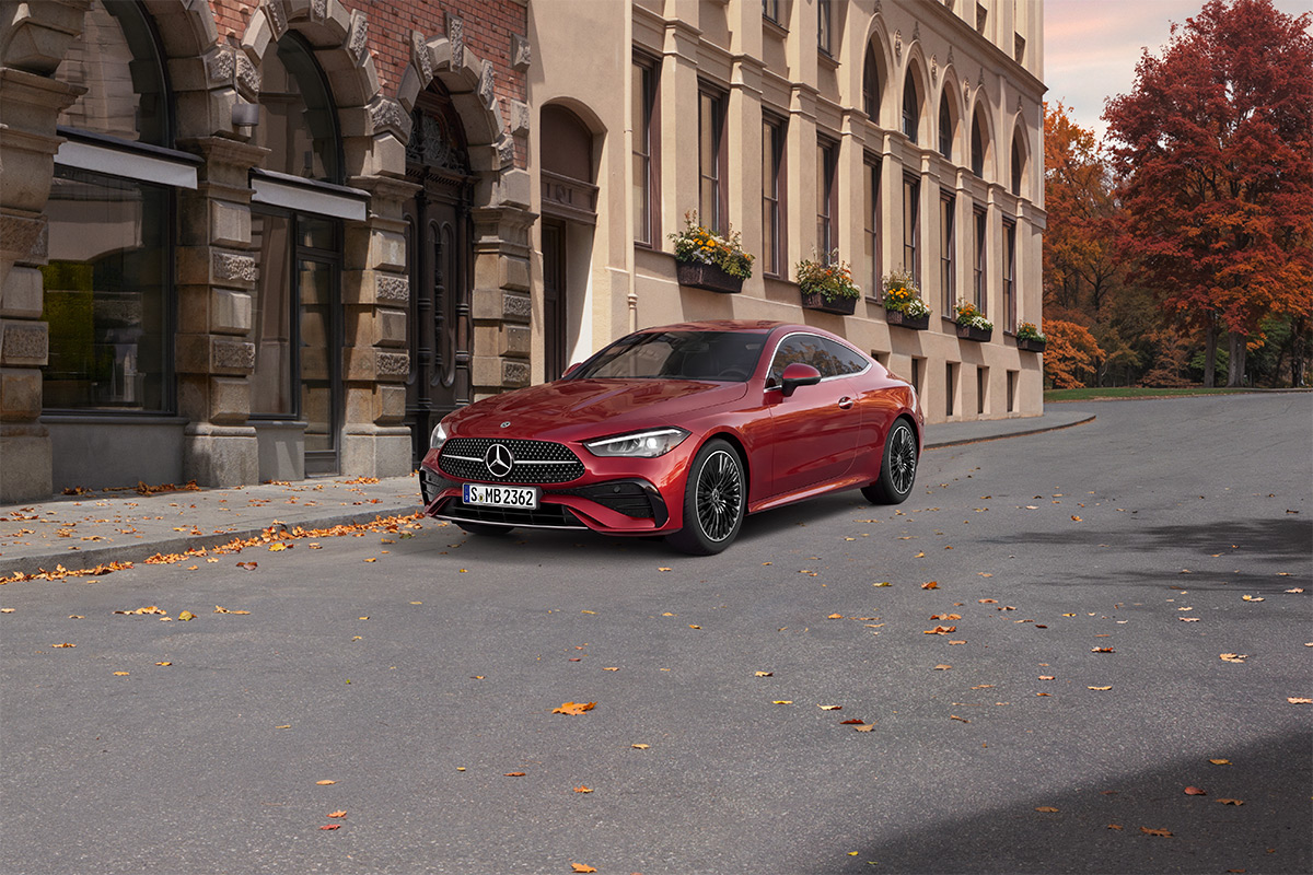 Rotes Mercedes-Benz CLE Coupe steht auf einer ruhigen Strasse vor einem historischen Gebaeude mit Arkadengaengen. Im Hintergrund sind herbstlich gefaerbte Baeume zu sehen.