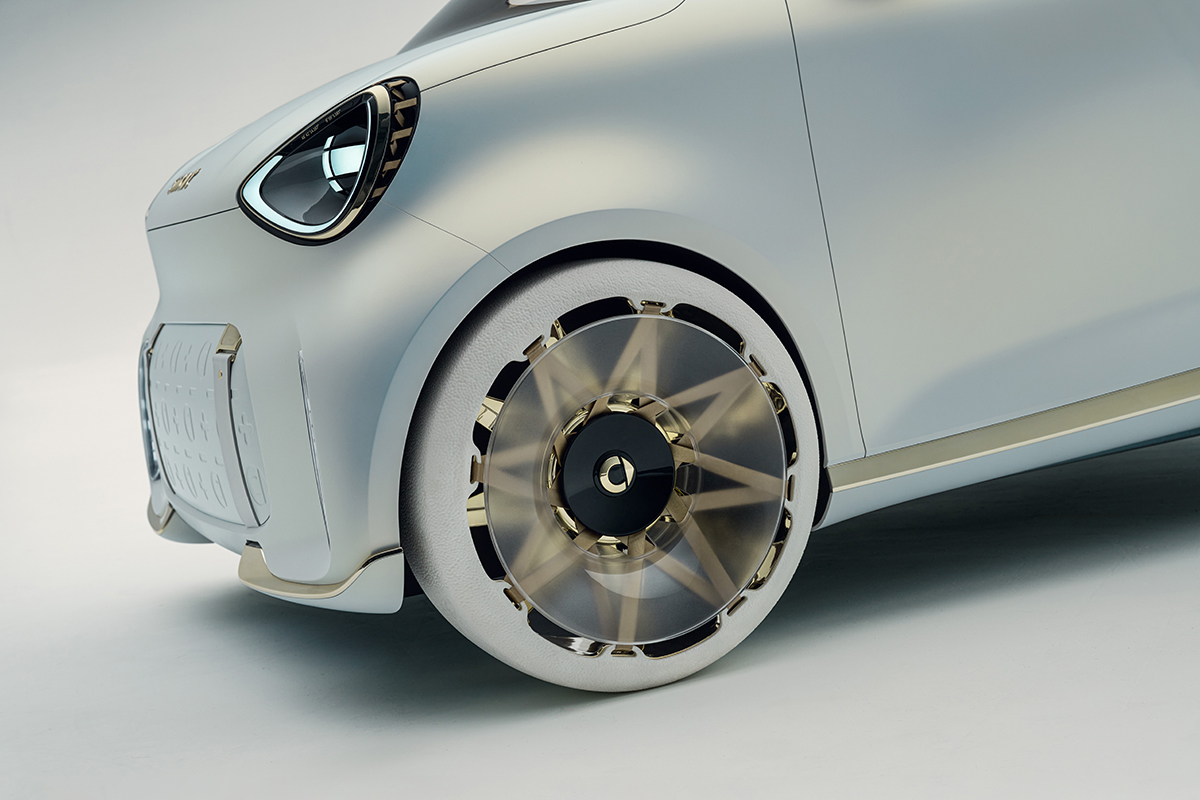 Detailaufnahme des futuristischen Vorderrads eines weissen Smart Concept Autos. Zu sehen sind eine weisse Reifenflanke und eine komplexe goldfarbene Felge mit transparenten Elementen.
