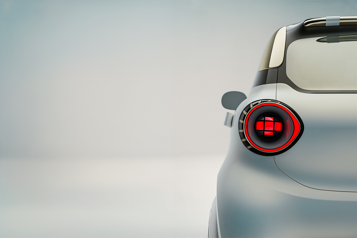 Detailaufnahme eines runden roten LED Ruecklichts eines weissen Smart Concept Autos. Die Heckleuchte hat ein markantes kreuzfoermiges Leuchtmuster und ist in die futuristische Karosserie integriert.