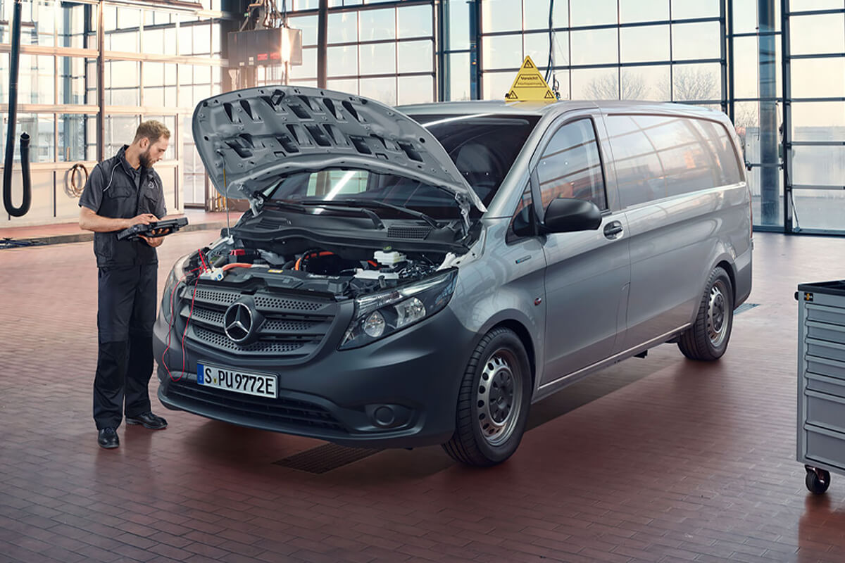 Ein Mechaniker steht an der offenen Motorhaube eines Nutzfahrzeugs.