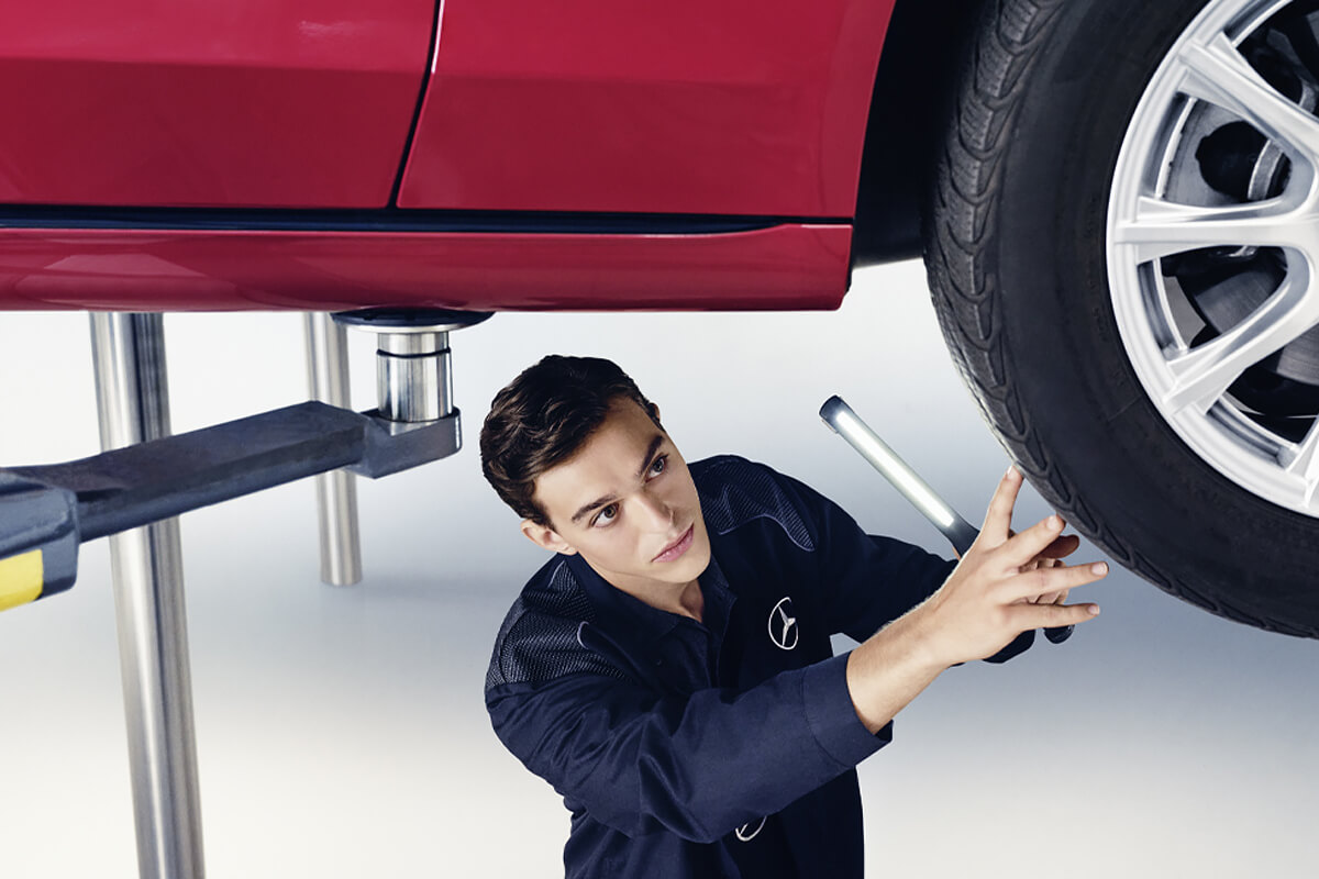 Mitarbeiter untersucht den Unterboden eines Fahrzeuges