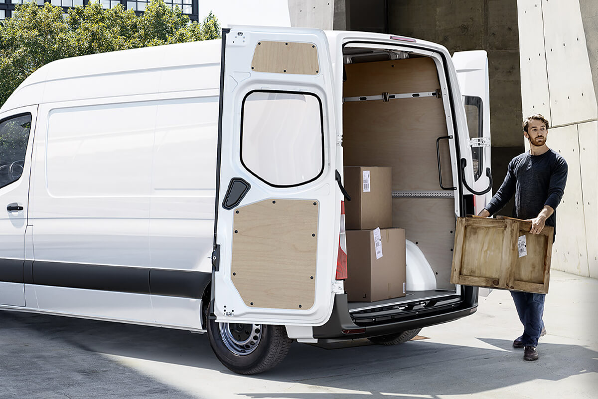 Eine Person trägt einen Karton zum Transporter.